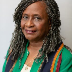 Dr. Brenda Greene is woman of color wearing a green, blue, yellow, and red shirt